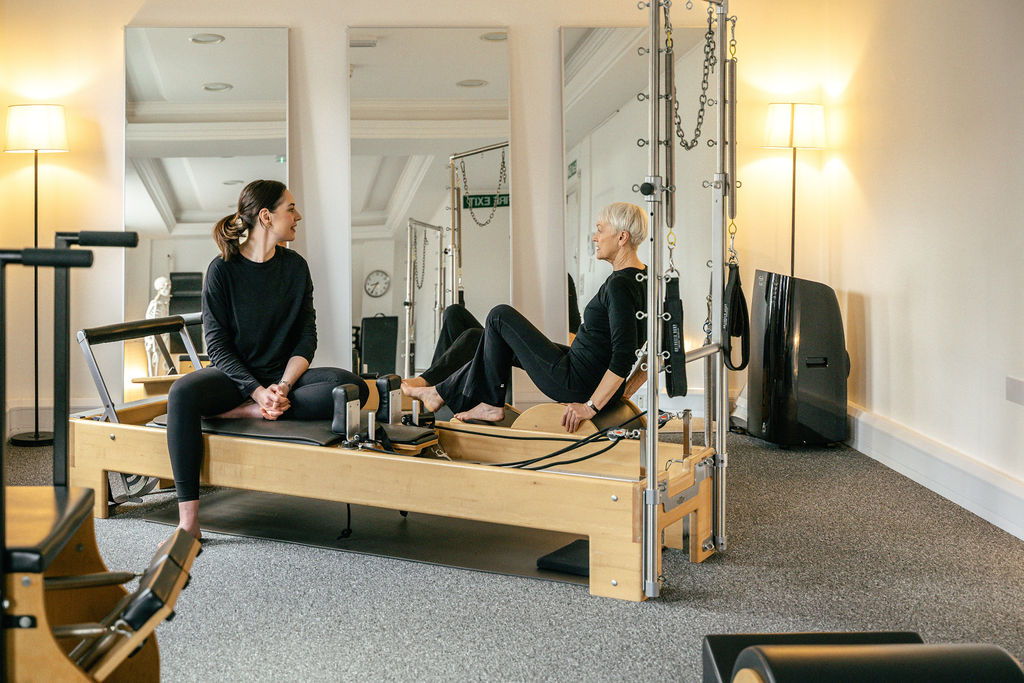 A teacher and client in York Pilates Space beside a Reformer